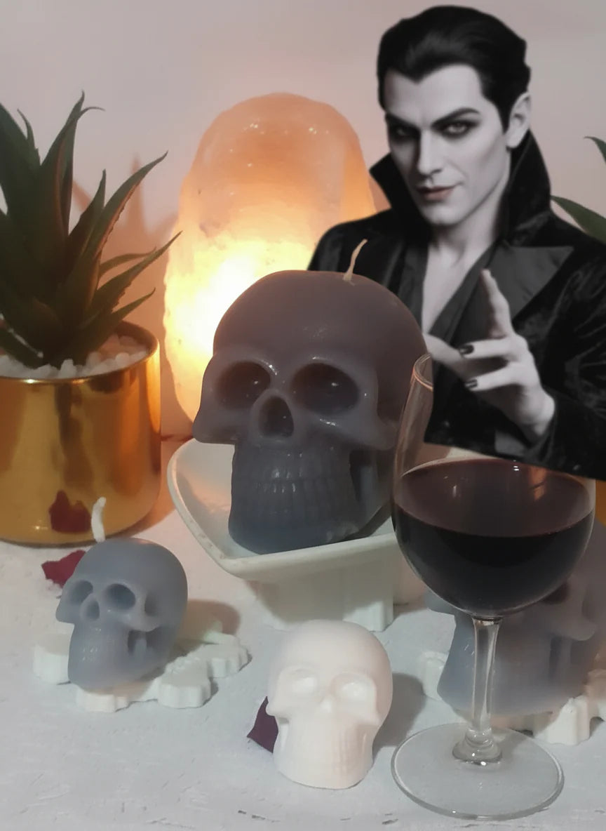 Skull-shaped candles with a villain in a black outfit and a glass of red wine on a table.